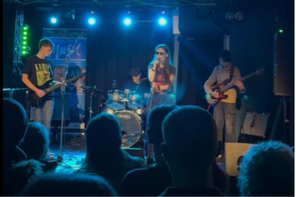 image of young people plying guitars on a stage at a venue