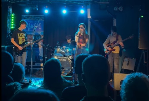 image of young people plying guitars on a stage at a venue