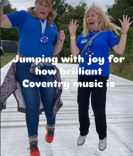 two members of Coventry music jumping up happily at Godiva Festival