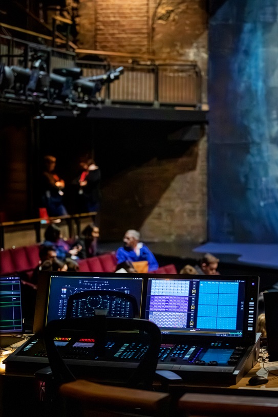  image of a computer console at the rear of a theatre with lots of information and lights
