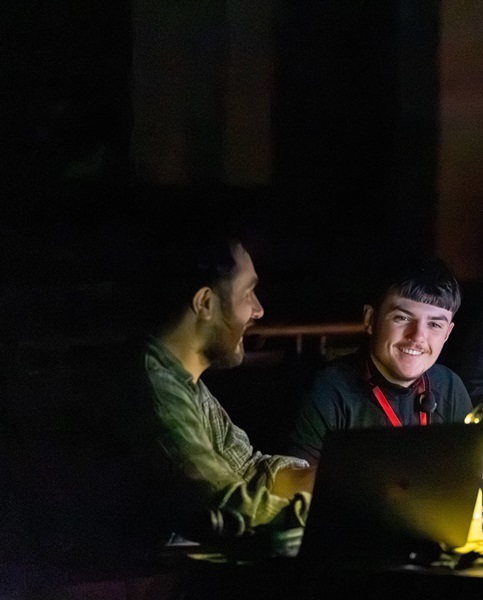 two people sat behind a desk looking at each other smiling