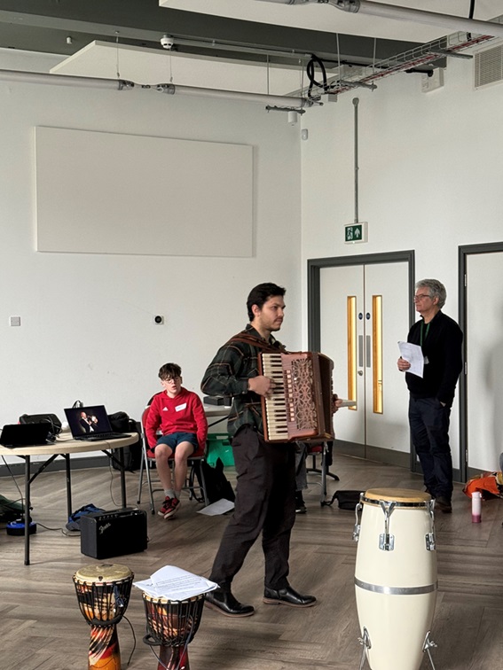 music teacher playing accordion in a room full of instruments