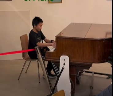 boy playing wooden grand piano
