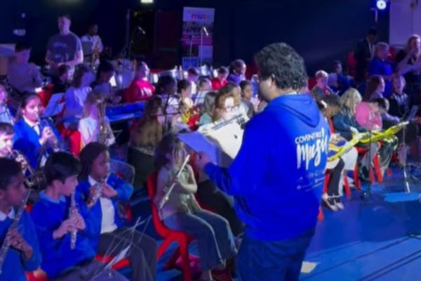 lots of children performing on a  mix of musical instruments at a concert in a dimly lit room
